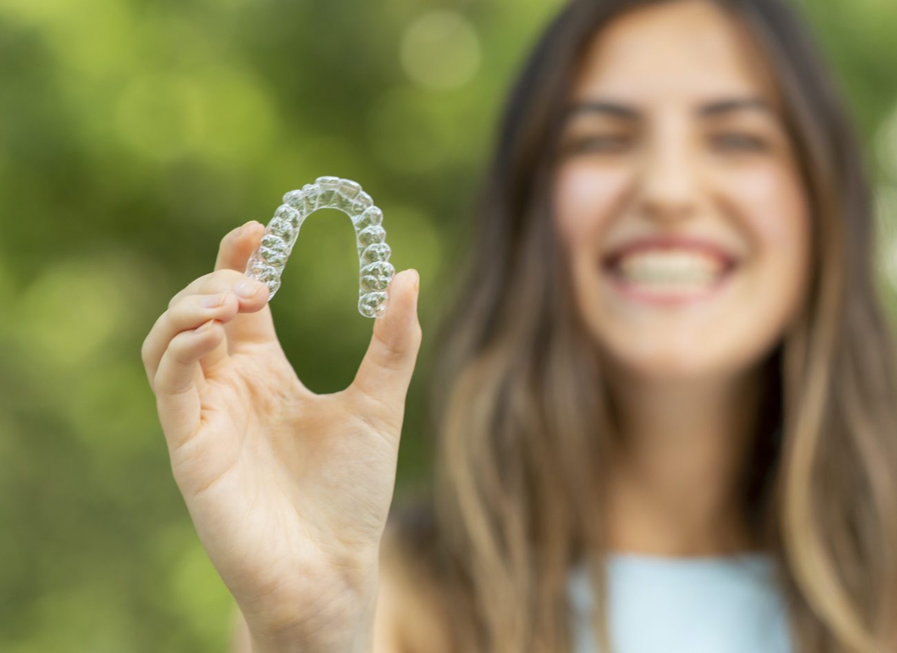 woman holding Invisalign clear aligner