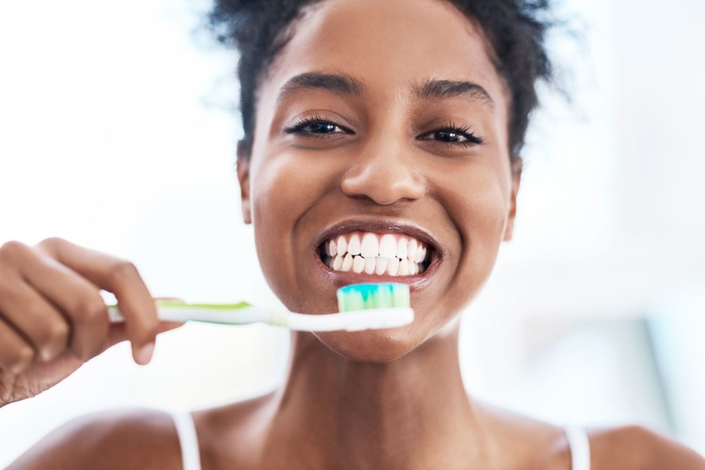woman holding a toothbrush about to brush her teeth oral hygiene dentist in Medford New Jersey